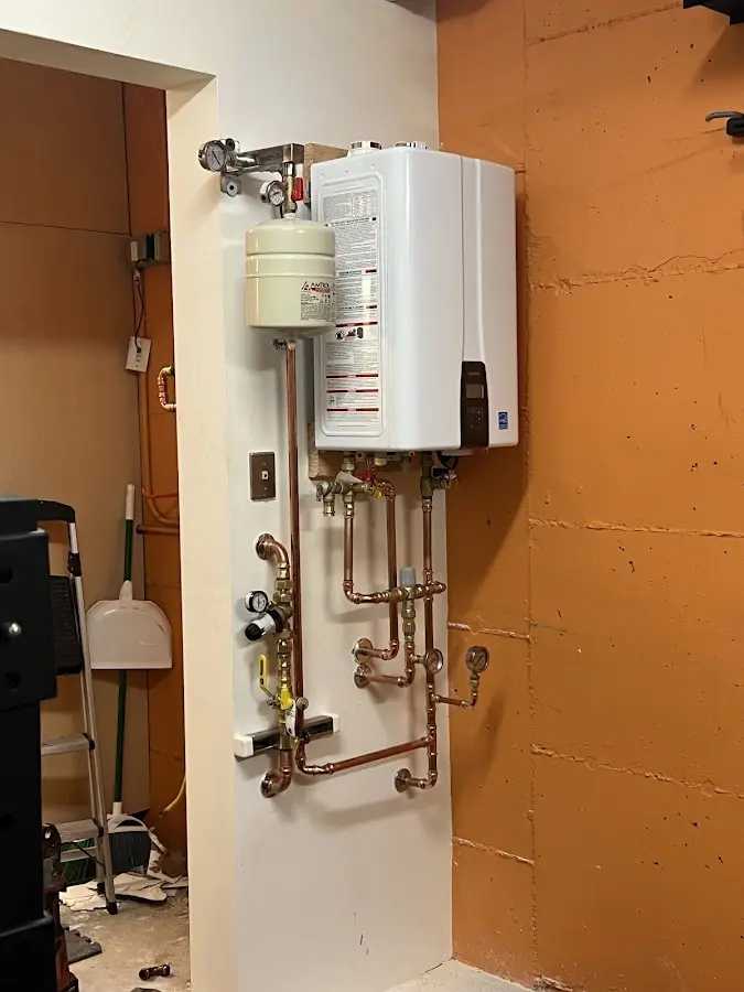 Plumbing technician inspecting water heater connections in North East